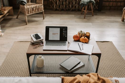 Comfortable home workspace featuring a laptop on a wooden desk with autumn-themed decoration.