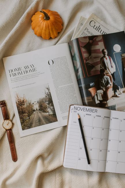 Cozy flat lay featuring a magazine, pumpkin, planner, and wristwatch, perfect for fall inspiration.