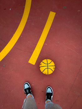 View from above of sneakers and a basketball on a red court in Barcelona, Spain.