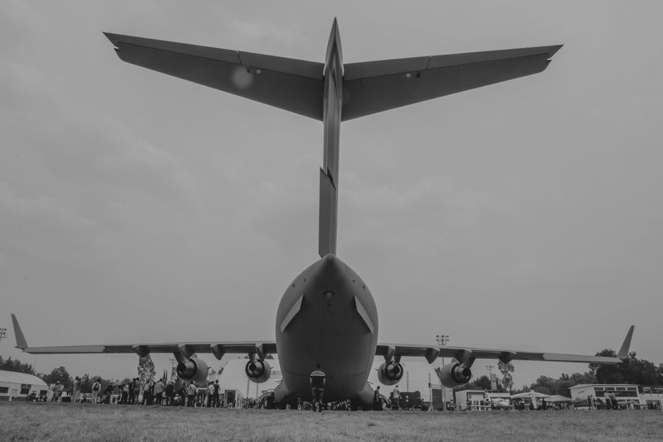 Black and white rear view of a large military aircraft on display outdoors.