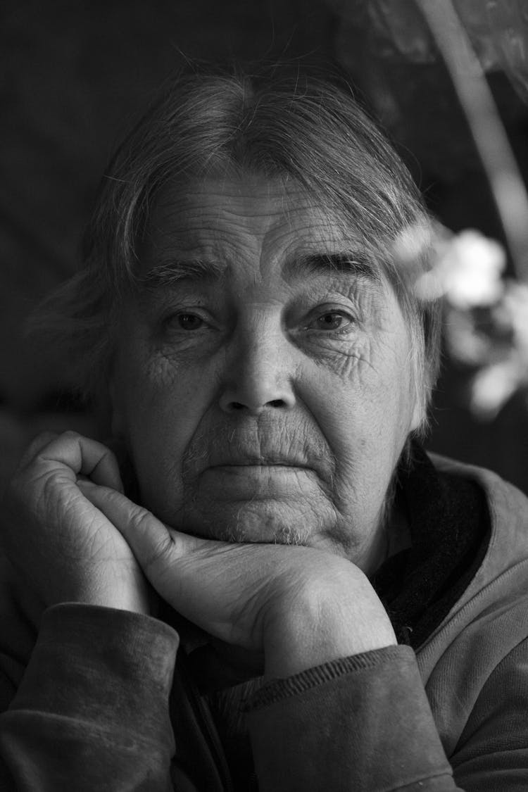 Old Woman Sitting And Propping Her Head With Hand