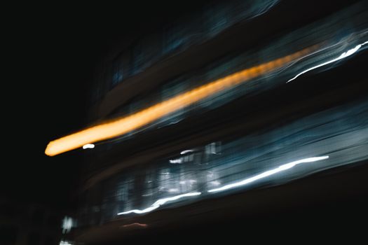 Abstract long exposure photo of light trails captured in motion depicting an urban setting at night.