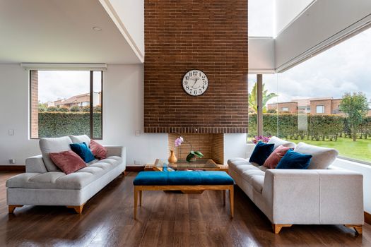 Bright and comfortable contemporary living room with brick fireplace and large windows.
