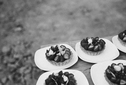 Close-up of strawberry tarts on ceramic plates in grayscale, creating a classic, artistic feel.