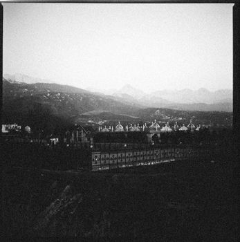 A classic black and white photograph of a cityscape with mountains in the background, showcasing unique architecture.