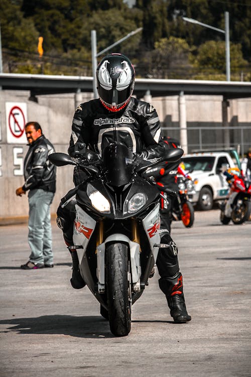Man in Black Motorcycle Helmet and Clothes Riding a Motorcycle