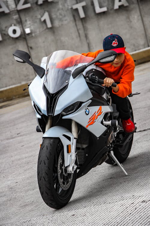 Photo of a Boy in an Orange Shirt Riding a Motorcycle