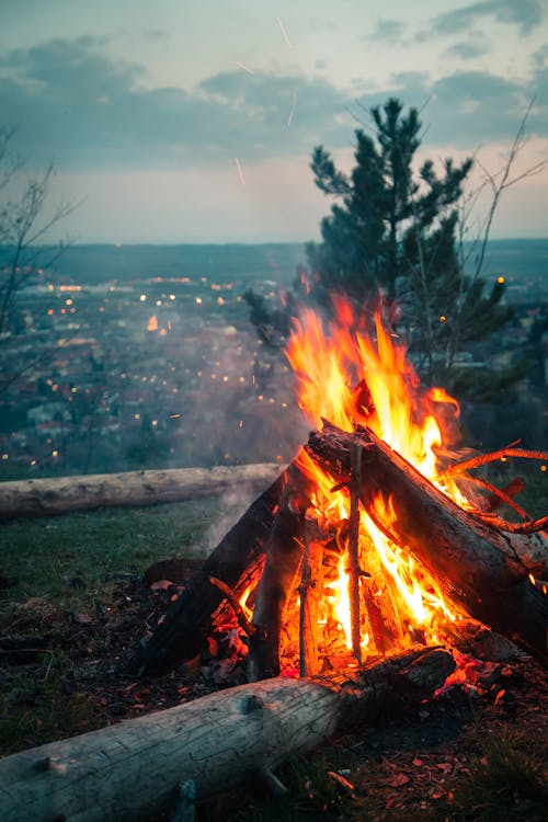 Free Photo of Bonfire Placed on High Ground in Front of City Under Cloudy Sky Stock Photo