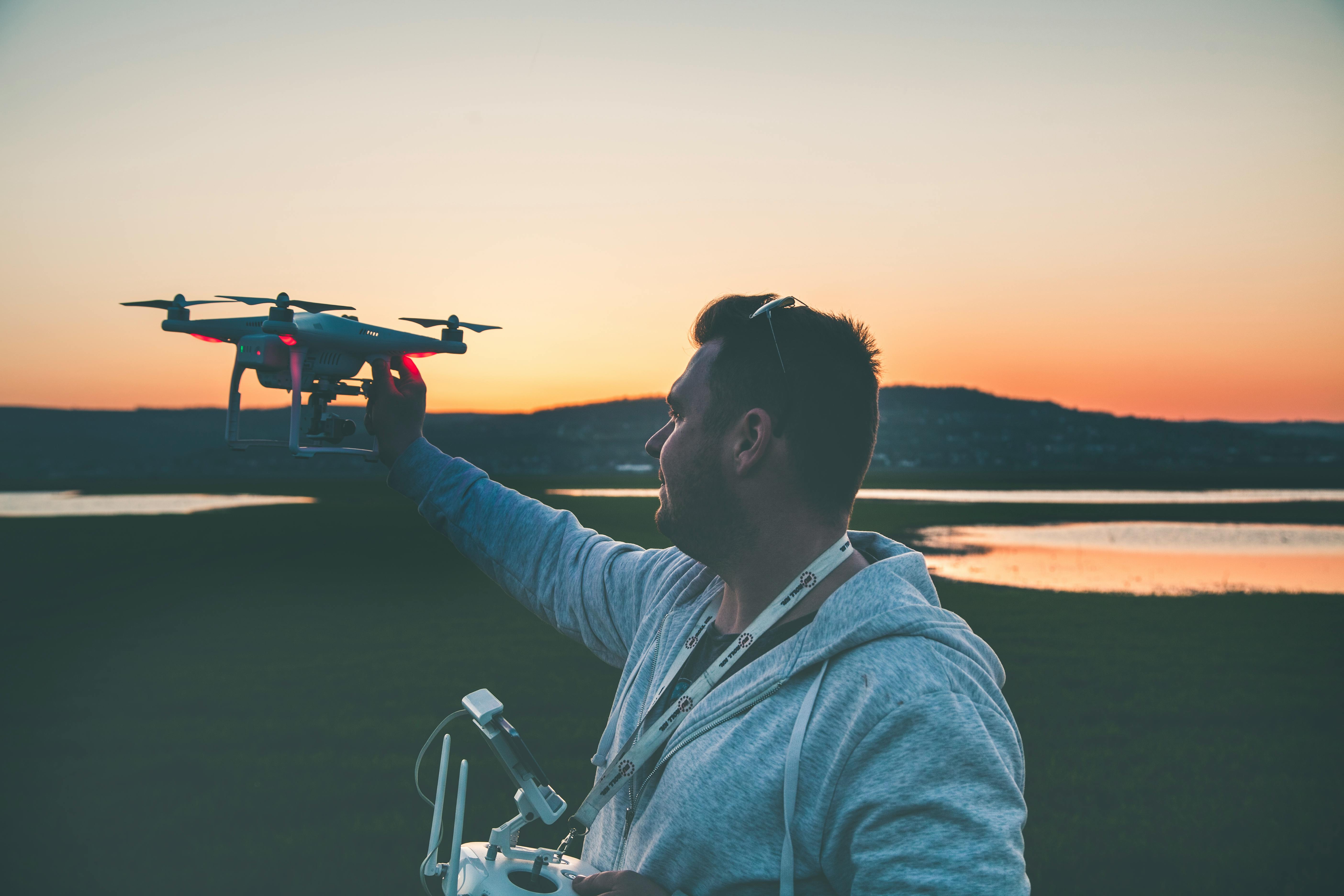 man in gray jacket holding black drone