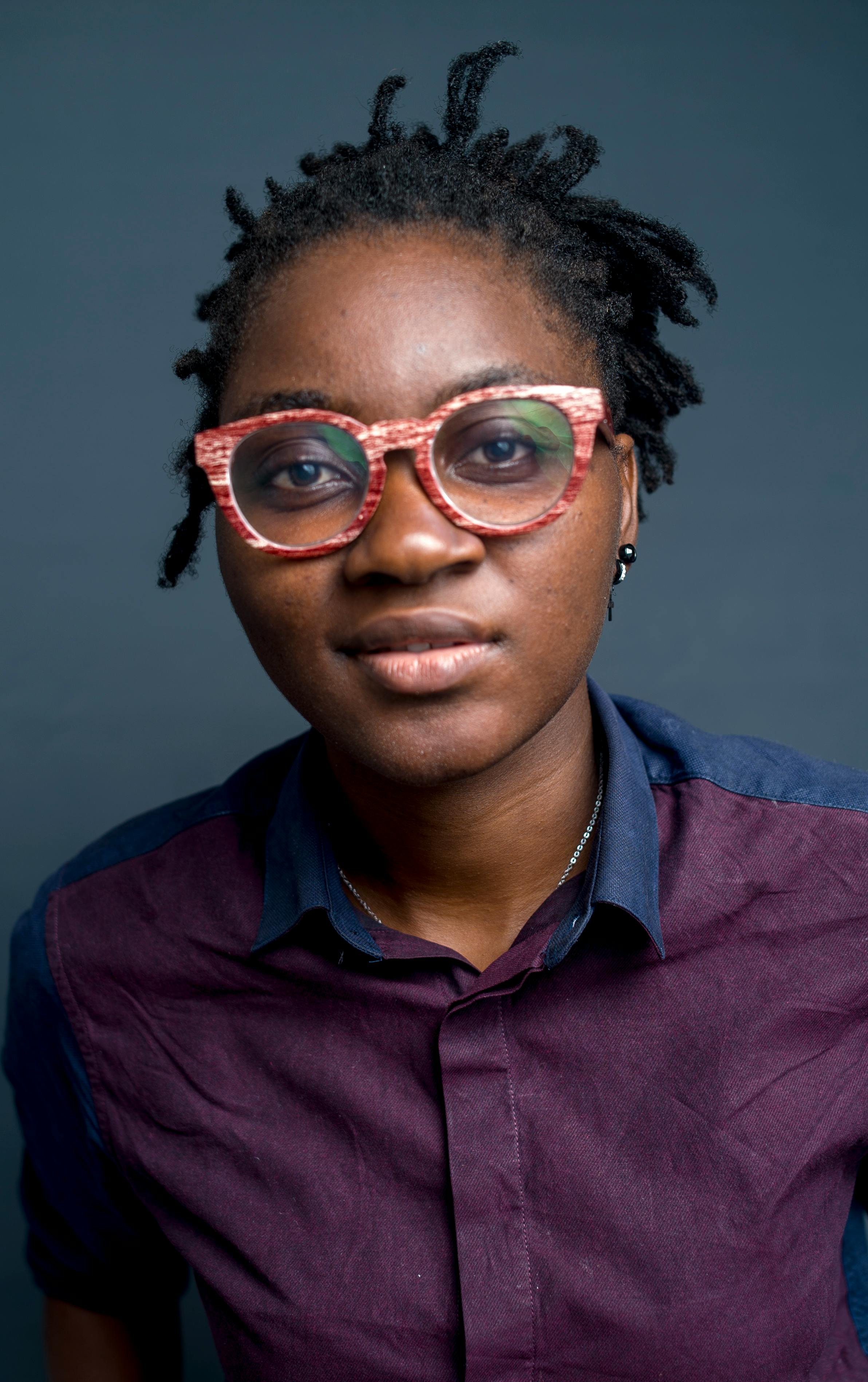 Studio portrait of a joyful woman wearing vibrant eyeglasses and a stylish shirt, exuding happiness and confidence.