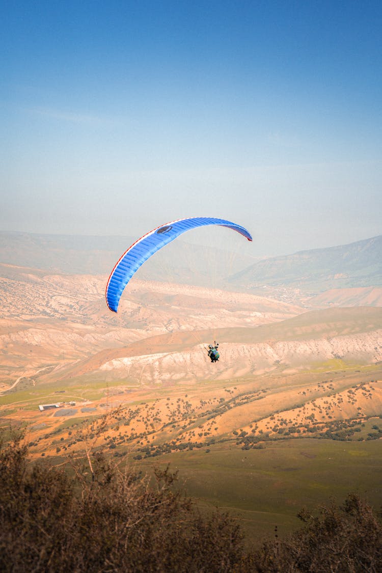 Paraglider Flying Over Hills