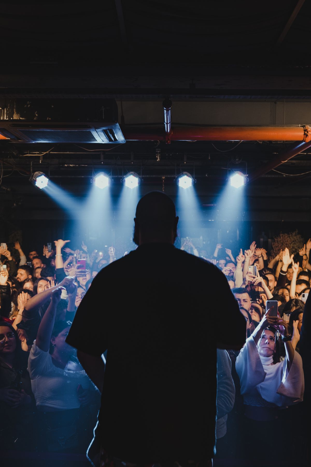 Performer facing a live audience holding smartphones