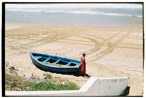 Man near Wooden Boat on Beach