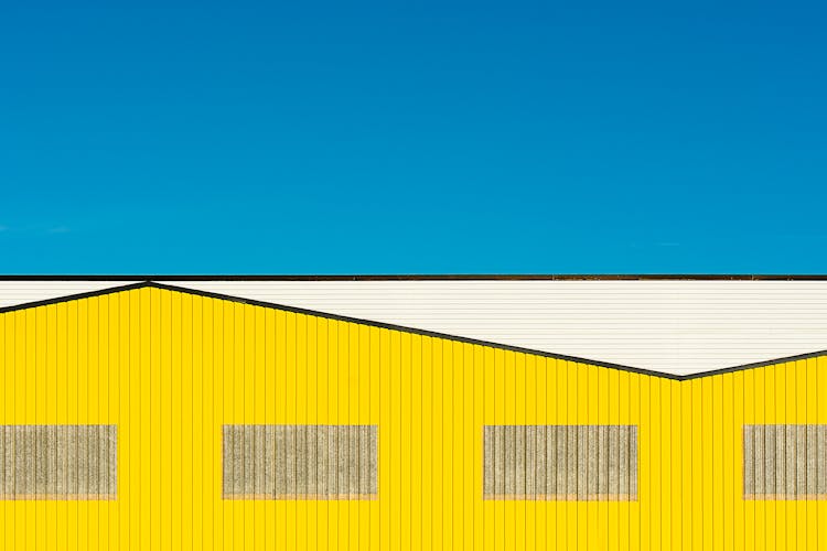 Abstract Image Of A Yellow Warehouse Against Blue Sky