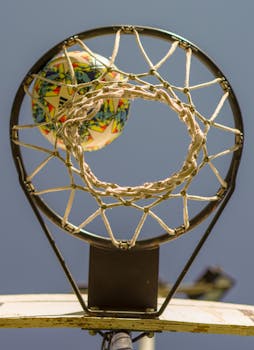 Basketball captured in motion as it successfully goes through the hoop from a low angle.