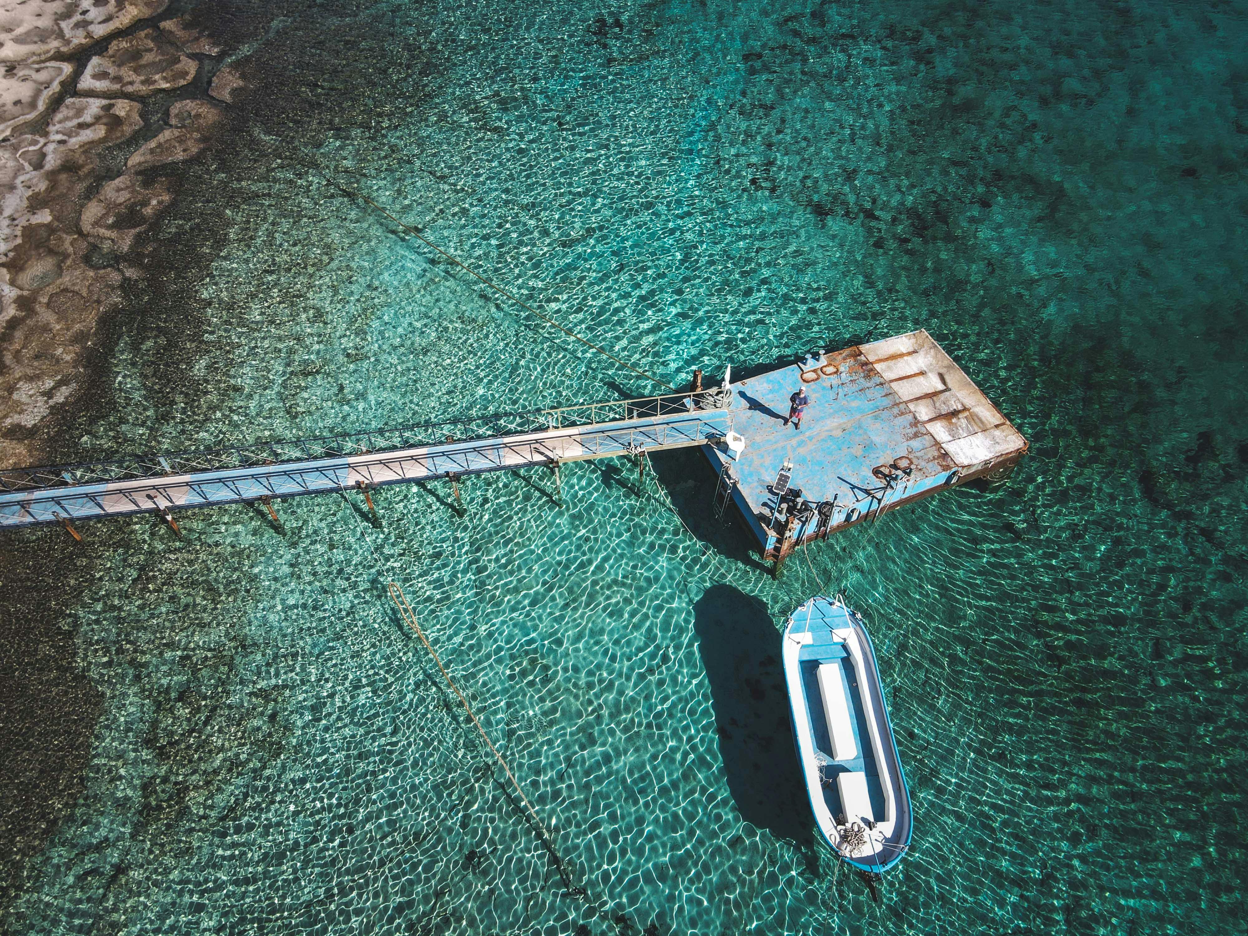 an drone shot of man controlling a drone on a platform on clear water