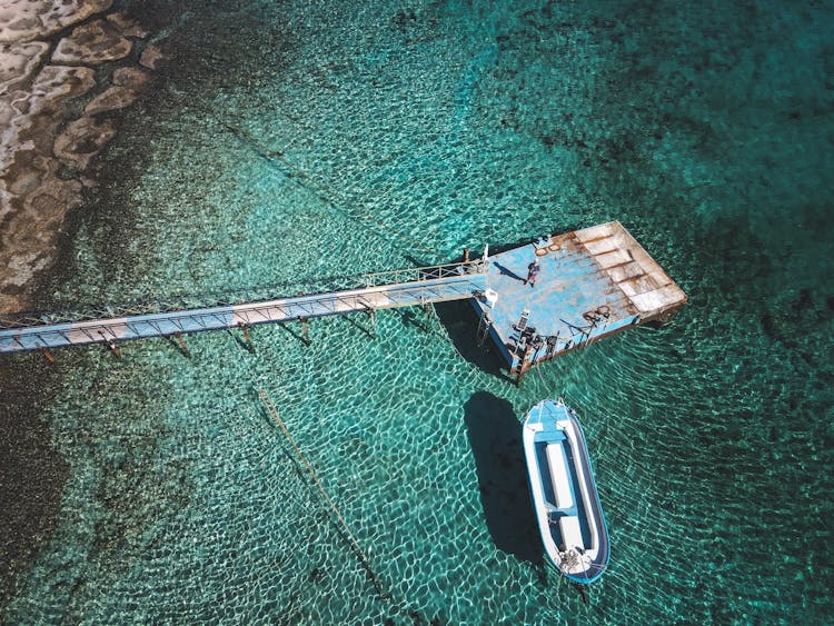 An Drone Shot Of Man Controlling a Drone On A Platform On Clear Water 