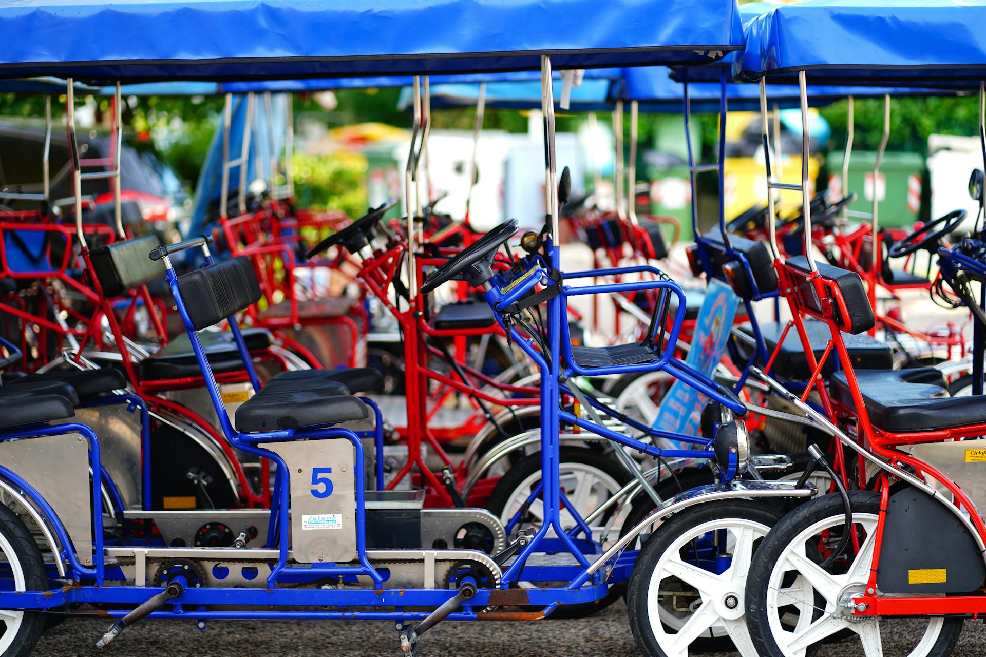 Vibrant red and blue quadricycles parked for rental in a sunny outdoor area.