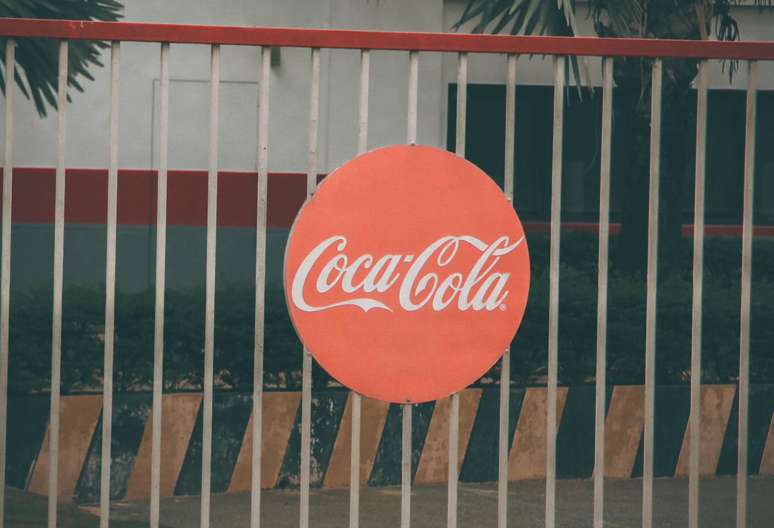 Coca-Cola logo displayed on a circular red sign, representing brand identity and trademark protection in visual design.
