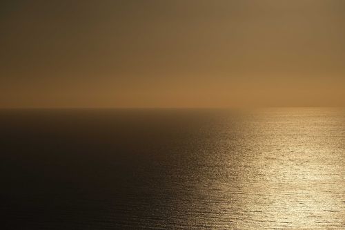 Free A serene view of the ocean at sunset, capturing the golden hues and calm waves. Stock Photo