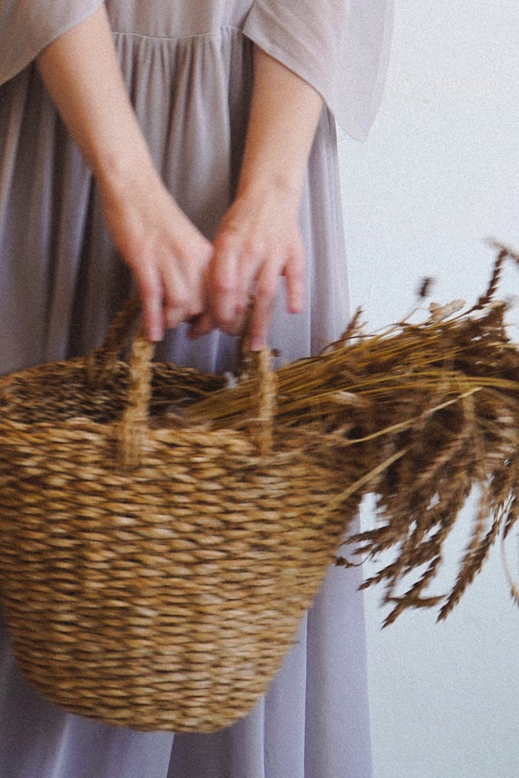 A Person Holding A Woven Basket With Wheat