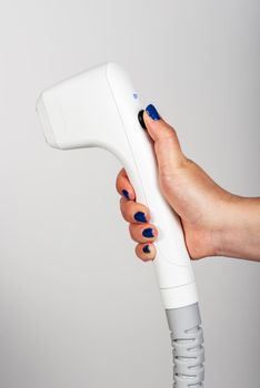 Close-up of a female hand holding a white ultrasound device against a white background.