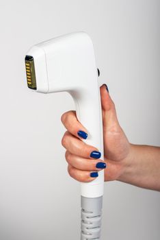 Female hand with blue nails holding a skin treatment machine for wrinkle reduction.