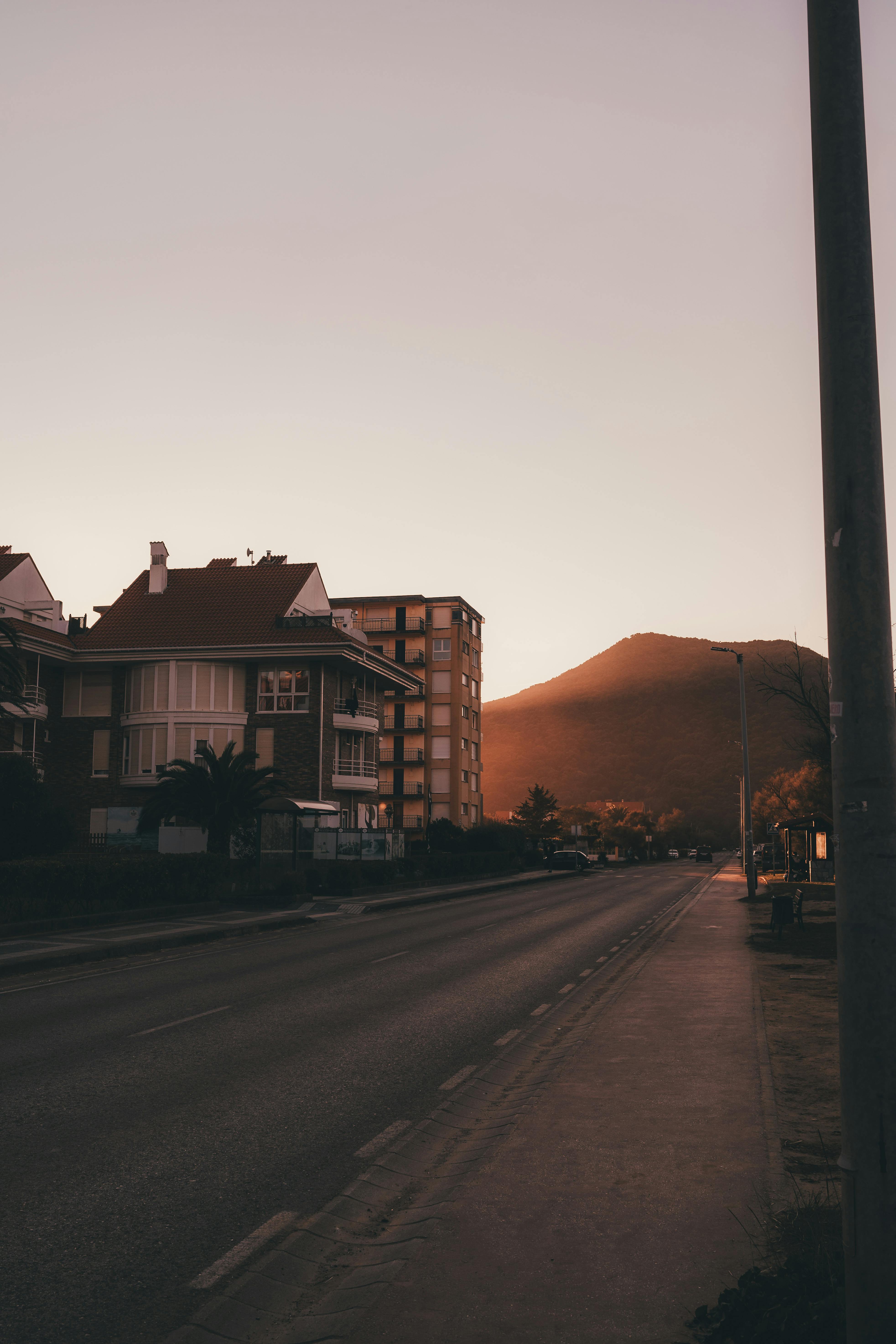 Serene urban street at sunset with distant hills and buildings in warm light.