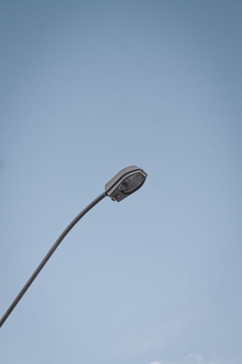 Free Single street light set against a clear blue sky, evokes simplicity in urban design. Stock Photo