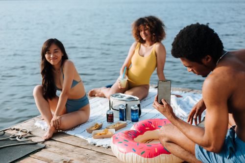 Free Group of diverse friends relaxing by the lake, enjoying summer vibes. Stock Photo