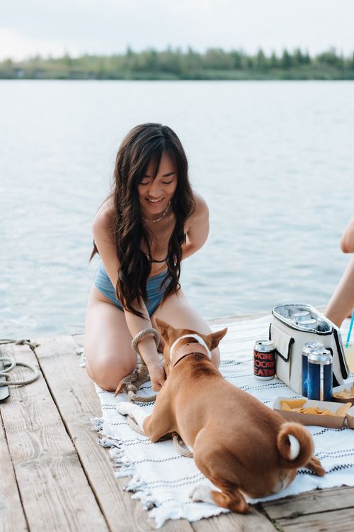 Free Young woman enjoys a summer day on a pier with her brown dog by the lake. Stock Photo
