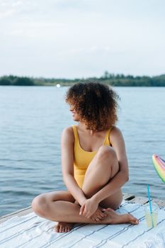 Woman in yellow swimsuit enjoying a peaceful moment by the lake in summer.