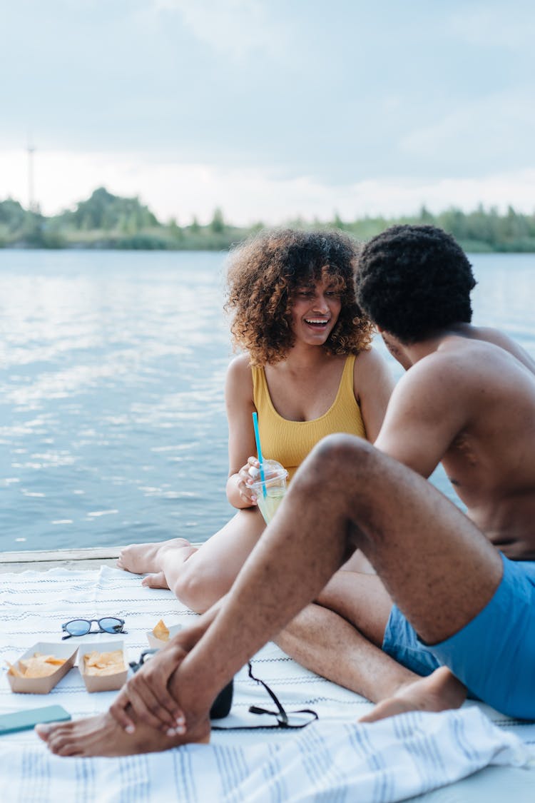 Couple Having A Picnic Near Body Of Water