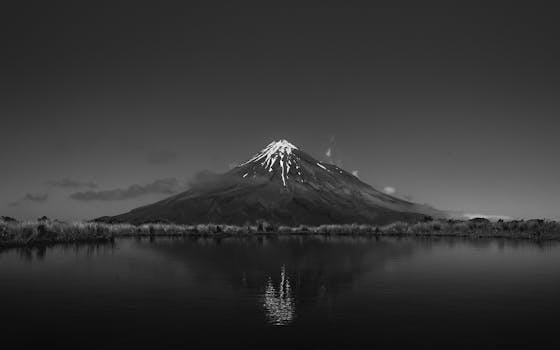 Breathtaking black and white view of Mount Taranaki with a tranquil lake reflection, New Zealand.