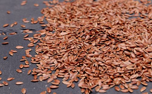 Free High-resolution close-up of nutritious flaxseeds scattered on a dark background, perfect for health and diet concepts. Stock Photo