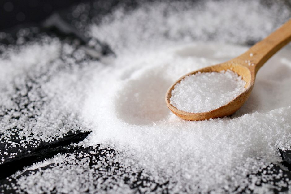 A close-up view of fine sea salt in a wooden spoon, perfect for culinary uses.