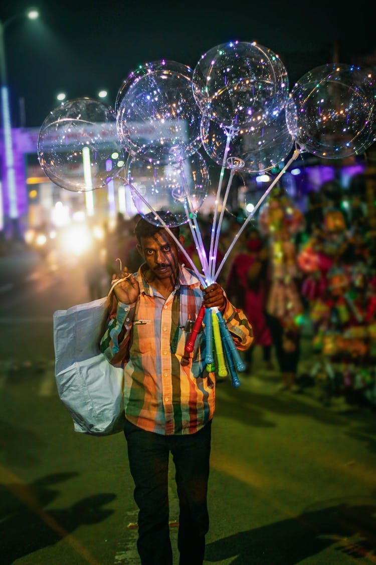 Man Selling Illuminated Balloons On Night Street