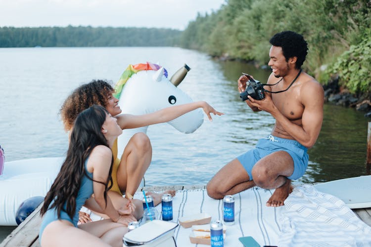 Man Taking Picture Of Friends During Lake Party 