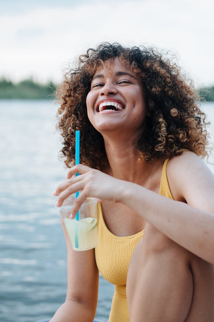 Laughing Woman Drinking Beverage By Lake