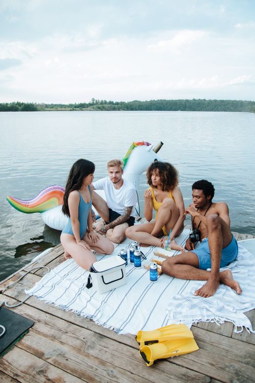 Free Group of friends enjoying a day by the lake with food, drinks, and a unicorn float. Stock Photo