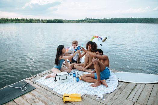 Group of friends enjoying a summer lakeside party with drinks and a unicorn float.