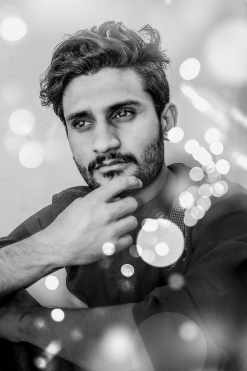 Free Elegant portrait of a young man in bokeh effect, emphasizing thoughtfulness and style. Stock Photo