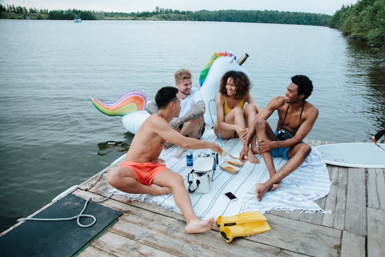 People Sitting On A Wooden Dock Having Fun