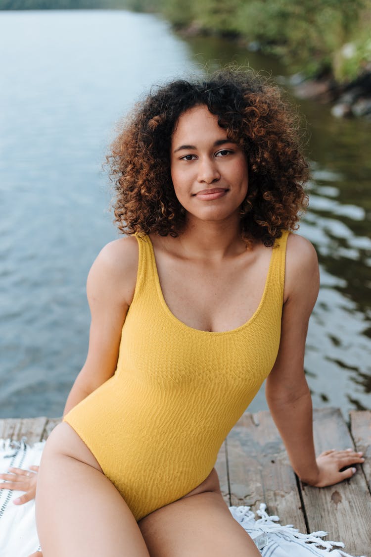 Woman In Swimsuit Sitting On Pier