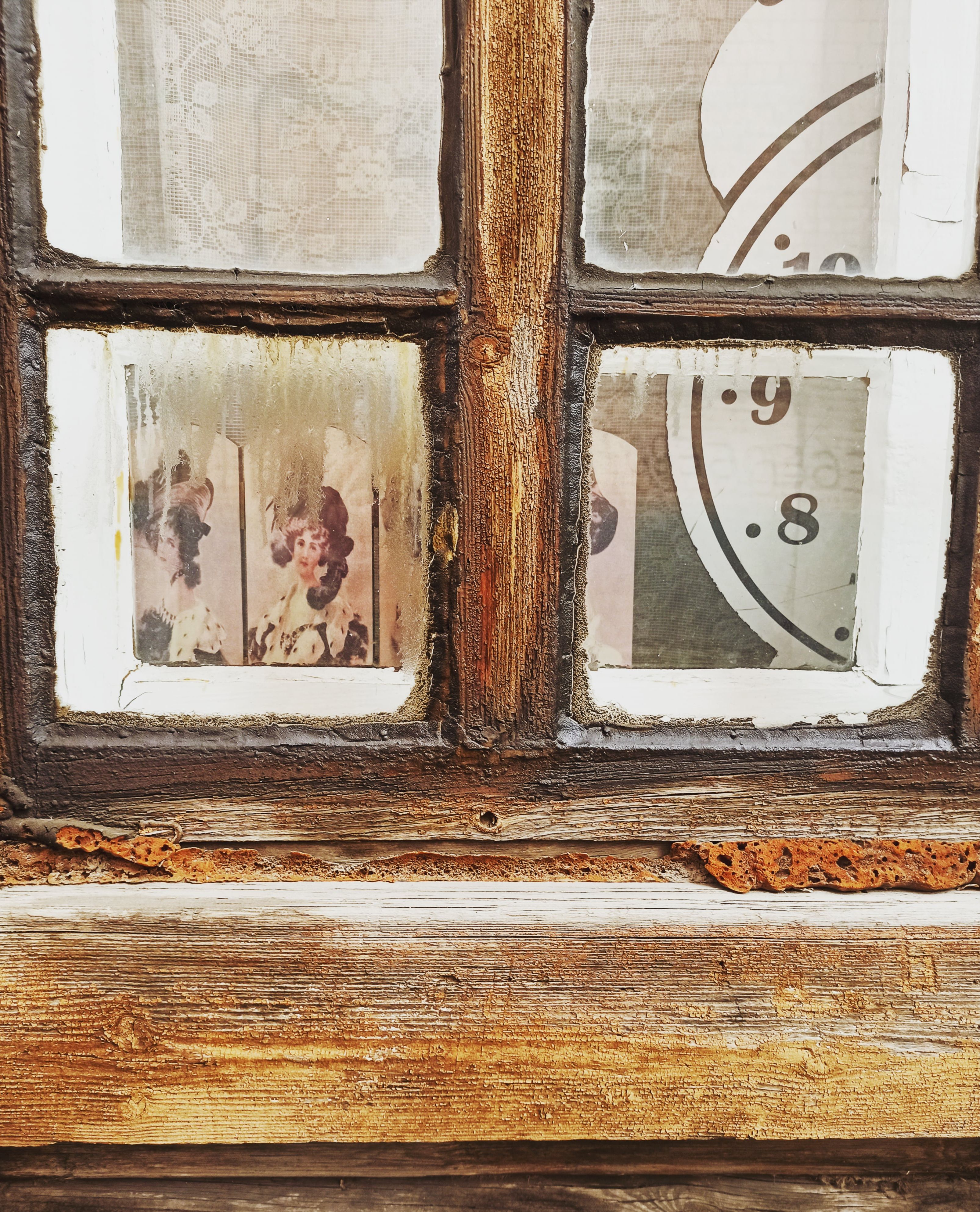 A close-up of a rustic window with vintage family photos behind glass.