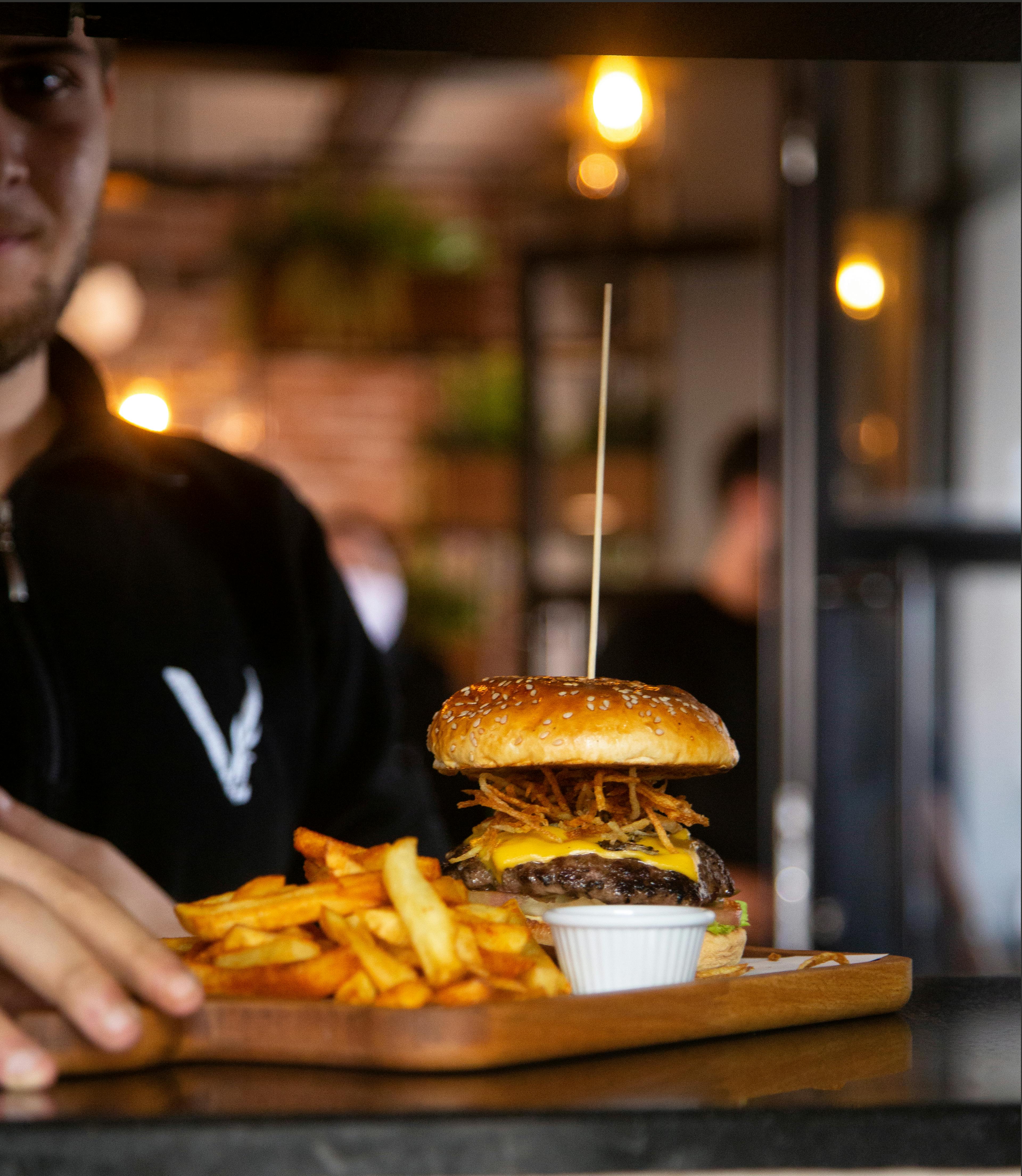 Delicious cheeseburger with crispy fries on a rustic wooden tray, served indoors in a cozy setting.