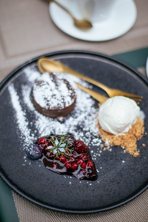 Free Gourmet dessert with chocolate fondant, ice cream, and berry compote on a black plate. Stock Photo