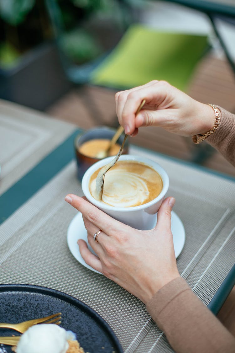 Woman Stirring Coffee In Cup