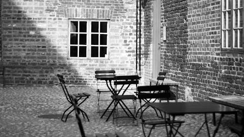 Grayscale Photo of 4-piece Dining Set Near Concrete Building