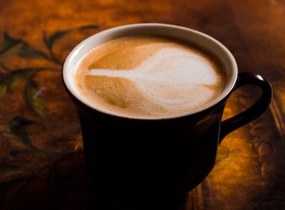 Cappuccino with latte art in a dark mug — photo by Johnny Willz on Pexels